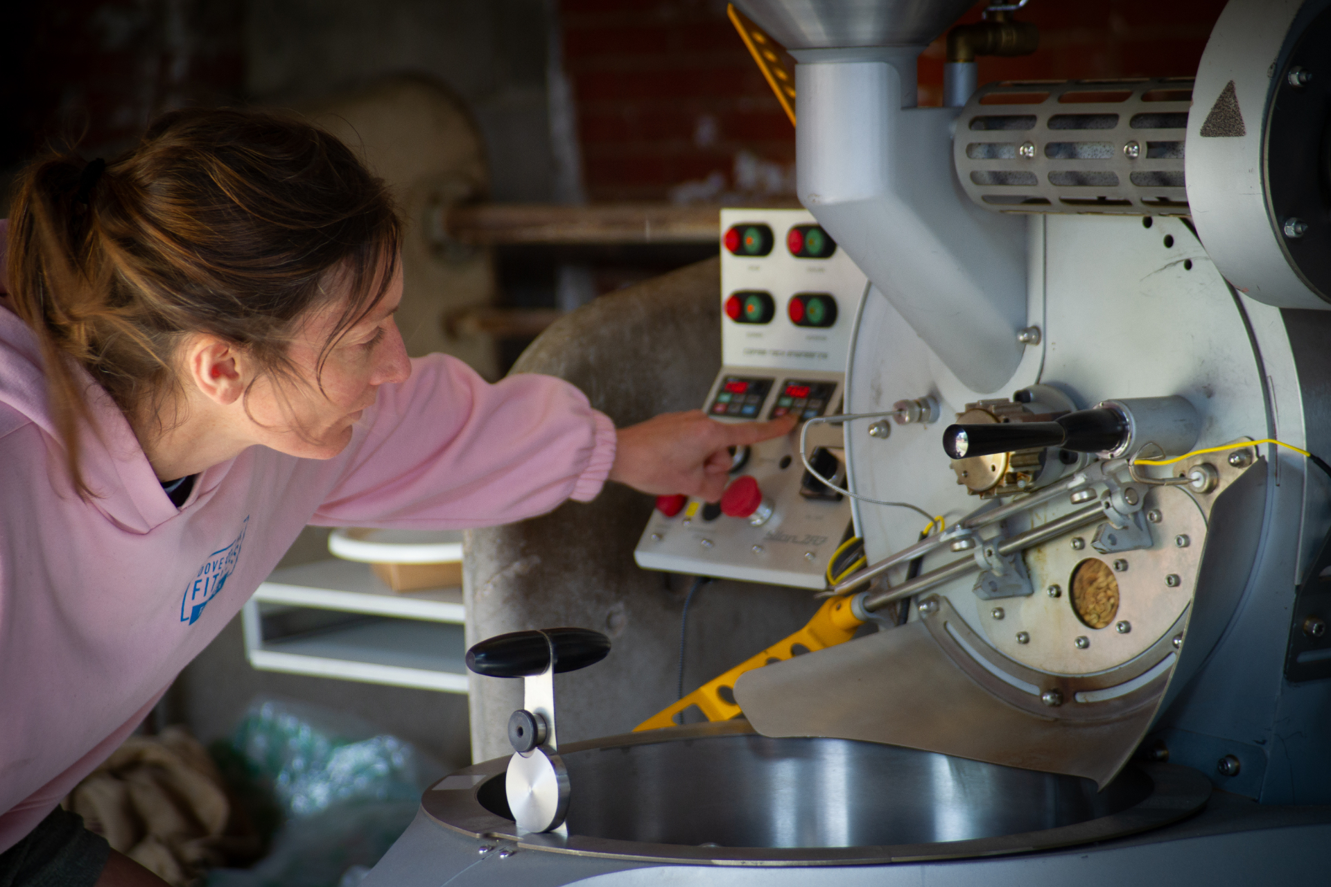Rachel roasting coffee on a manual gas roaster in her farm shed